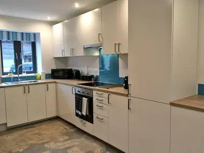 a kitchen with white cabinets and a sink and a stove at Ty Glo Cottage in Brecon