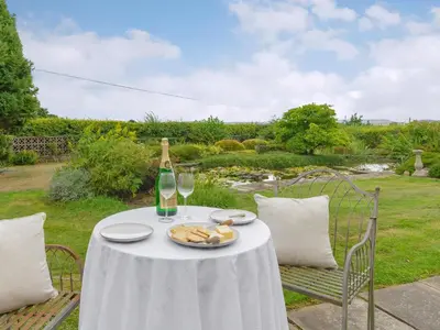 a table with a bottle of wine and a plate of food at Mortimer Trail Mews in Aymestrey