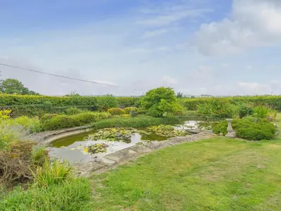 a garden with a pond with flowers in a field at Mortimer Trail Mews in Aymestrey