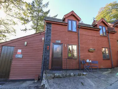 a wooden house with a red exterior at Cedar Cottage in Llanidloes