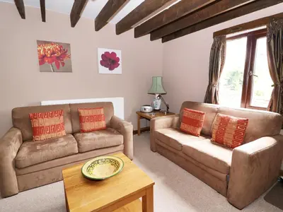 a living room with two couches and a coffee table at Cedar Cottage in Llanidloes