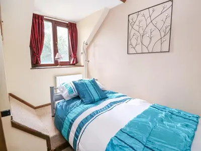 a bedroom with a bed with blue and white sheets at Beech Cottage in Llanidloes