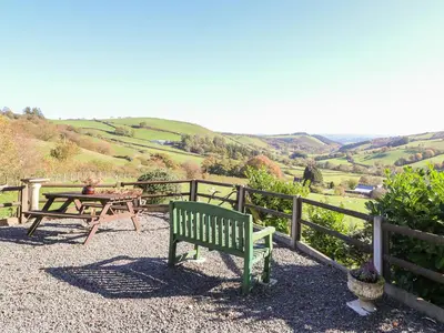 a green bench sitting next to a wooden fence at Oak Cottage in Llanidloes