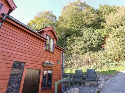 a red house with two chairs sitting outside of it at Oak Cottage in Llanidloes