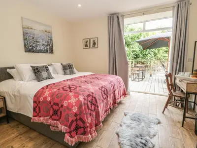 a bedroom with a bed with a red blanket at Rhianwen, Plas Moelfre Hall Barns in Llangadwaladr