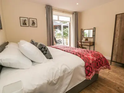 a bedroom with a bed with white sheets and a window at Rhianwen, Plas Moelfre Hall Barns in Llangadwaladr
