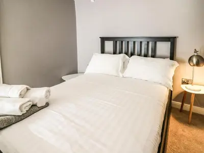 a bedroom with a bed with white sheets and pillows at Water Street in Aberaeron