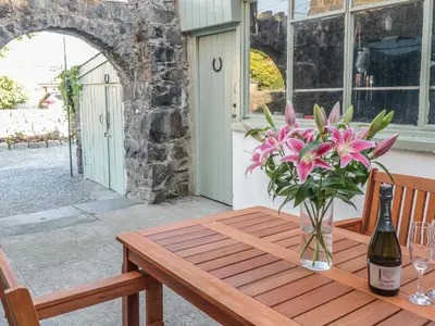 a wooden table with a bottle of wine and flowers on it at Y Cilgwyn in Blaenau-Ffestiniog
