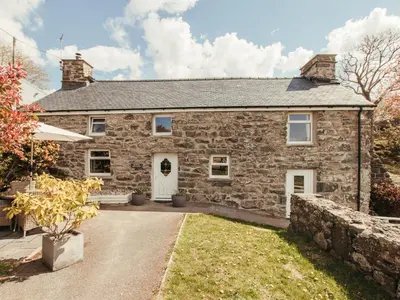 an exterior view of a stone house with a driveway at Cefn Uchaf Cottage in Llanbedr