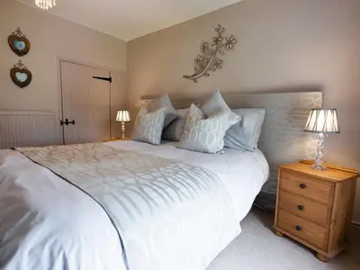 a bedroom with a large white bed and two lamps at Cefn Uchaf Cottage in Llanbedr