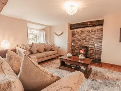 a living room with a couch and a fireplace at Cefn Uchaf Cottage in Llanbedr