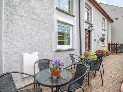 a patio with tables and chairs and flowers at Y Bwthyn in Llanegryn
