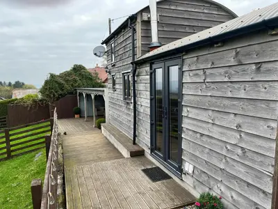 a house with a wooden deck next to a building at Shepherds Cabin at Titterstone in Farden