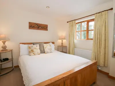 a bedroom with a bed with white sheets and a window at Old Hall Barn 1 in Church Stretton