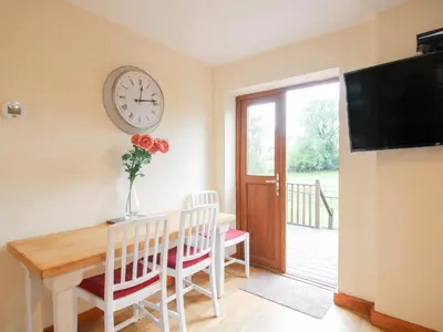 a dining room with a table and a clock on the wall at Old Hall Barn 1 in Church Stretton