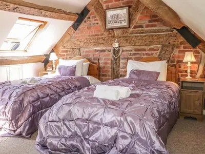 two beds in a room with a brick wall at Garden Cottage in Ludlow