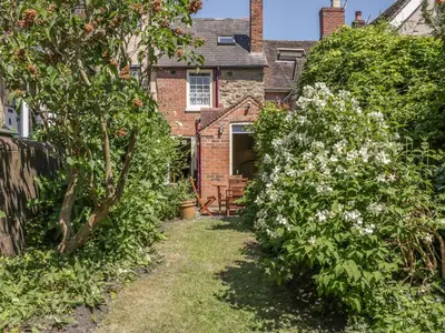a garden in front of a brick house at Garden Cottage in Ludlow