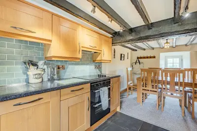 a kitchen with wooden cabinets and a dining room at Gwrtheyrn in Dyffryn