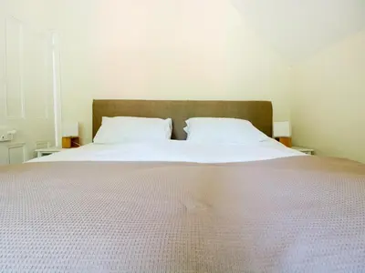 a bedroom with a large bed with white sheets and pillows at School House in Builth Wells