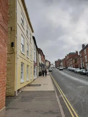 two people walking down a street next to a yellow building at 138a Old Star & Garter in Ludlow
