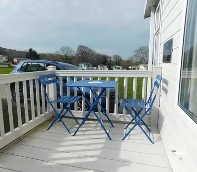 two blue chairs and a table on a balcony at Dyfed 23 in Borth