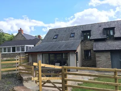 a house with a wooden fence in front of it at Llwyn Llwyd Cottage in Brecon