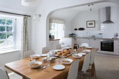 a dining room with a wooden table and a kitchen at The Old House, Llwyn Madoc in Llanwrtyd Wells