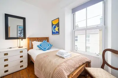 a bedroom with two beds and a dresser and a window at Awelfryn in New Quay