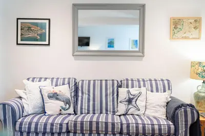 a blue and white striped couch with pillows and a mirror at Awelfryn in New Quay