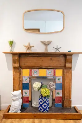 a mirror on top of a fireplace with flowers at Awelfryn in New Quay
