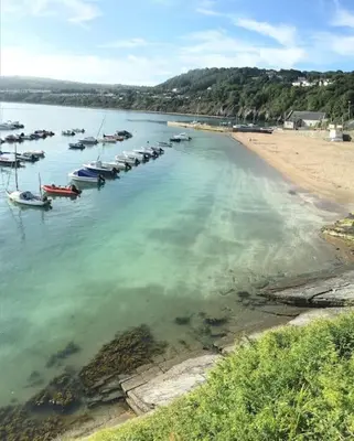 a group of boats in the water near a beach at Awelfryn in New Quay
