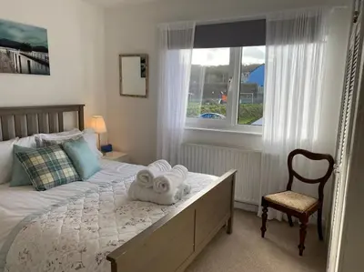 a bedroom with a bed and a chair and a window at Awelfryn in New Quay