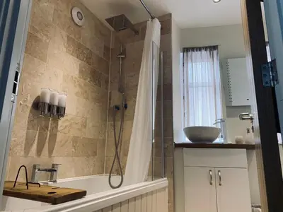 a bathroom with a shower with a tub and a sink at The Stowe in Shrewsbury