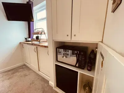 a kitchen with a black microwave in a cabinet at The Stowe in Shrewsbury