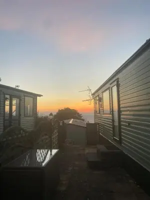 a house with the sun setting in the background at Hendre Coed Isaf Caravan Park in Barmouth