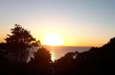 a sunset over the ocean with the sun in the sky at Hendre Coed Isaf Caravan Park in Barmouth