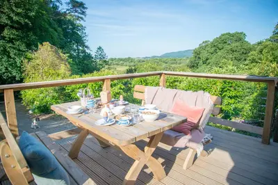 a wooden table and chairs on a deck at Little Kestrel Cabin in Pennal