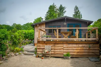 a tiny house with a deck on the side of it at Little Kestrel Cabin in Pennal