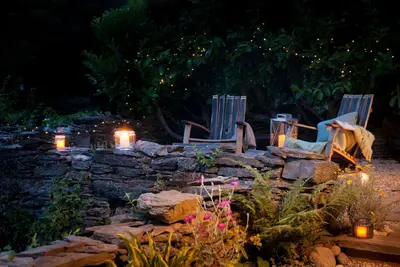 two chairs and candles in a garden at night at Little Kestrel Cabin in Pennal