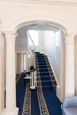 a staircase with blue carpet and white columns at No 47 Marine Terrace in Aberystwyth