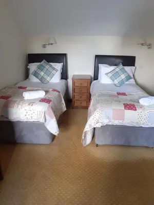 a bedroom with two beds and a dresser in it at The Carthouse in Aberystwyth