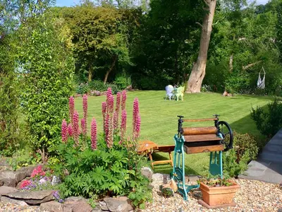a park bench in a garden with pink flowers at Brecon Boutique Breaks Wild Land in Sennybridge