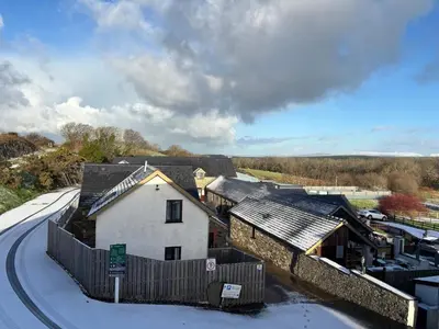 a building with snow on the ground next to a road at The Workshop in Aberystwyth