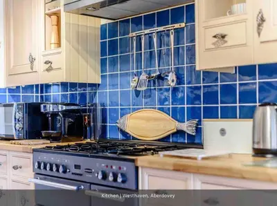 a kitchen with blue tiles on the wall and a stove at Westhaven One in Aberdyfi