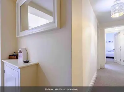 a hallway with a mirror and a white wall at Westhaven One in Aberdyfi