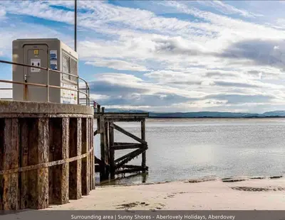 a pay phone sitting on a dock next to the water at Westhaven One in Aberdyfi