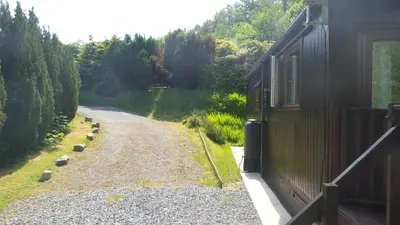 a dirt road next to a building and a road with trees at 28 Riverside, Caer Beris Holiday Park in Builth Wells