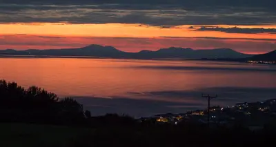 a sunset over a body of water with mountains at Enlli Fach cabin sleep's 2 adults and 2 children 2 dogs welcome not suitable for contract workers due to parking height restrictions in Borth