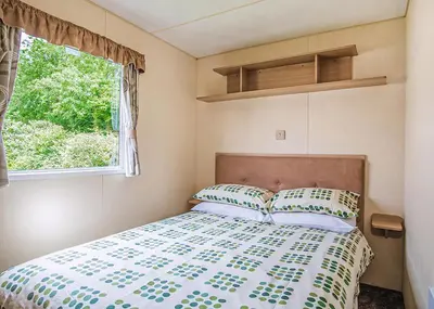 a bed in a small room with a window at The Village Holiday Park in New Quay