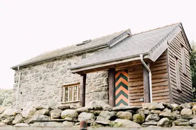 a log cabin with a colorful painting on the door at The Barn at Ty Beic in Bala